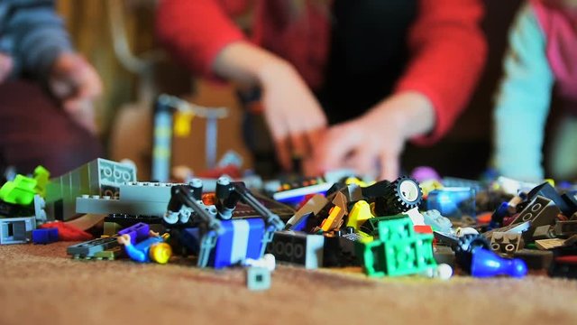 Family of three people chooses details of construction toys to create robot