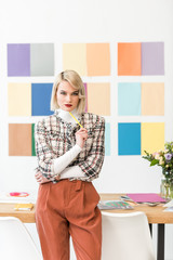 attractive fashion magazine editor with colors palette on wall in modern office