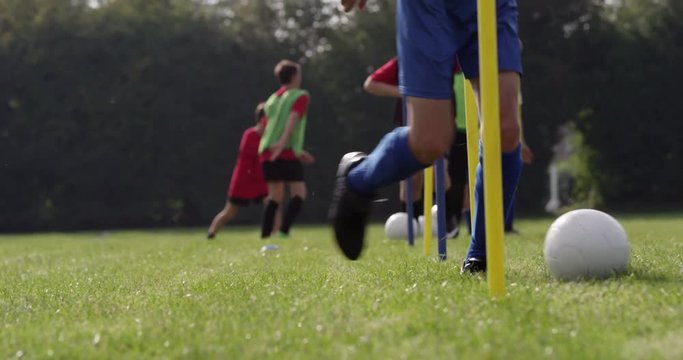 Boys dribbling a soccer ball around flag poles on a sports field. Shot on RED Epic.