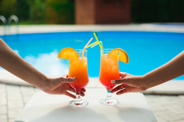 Bikini women in pool relaxing with juice, young beautiful sexy girls resting in vacation on summer season at swimming pool