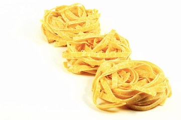 Three traditional italian pasta tagliatelle nests isolated on white background.