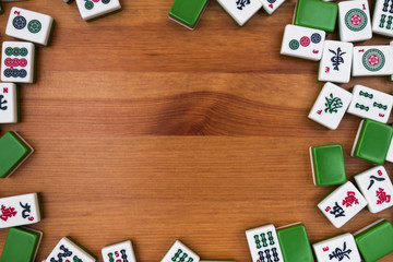 White-green tiles for mahjong on a brown wooden background. Empty place in the center.