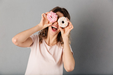 Playful woman in t-shirt having fun while holding donuts