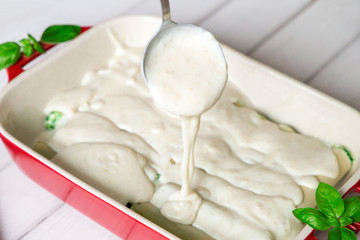 Pouring bechamel sauce on cannelloni.