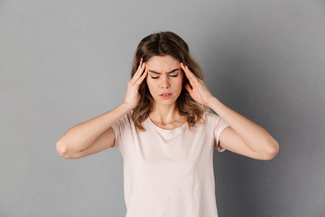 Confused woman in t-shirt having headache while holding head