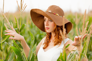 Young girl in hat at corn field