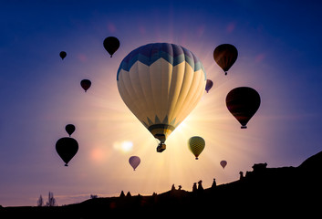 Silhouettes of hot air balloons flying at sunrise over Cappadocia landscape. Active leisure and adventure on Turkey.