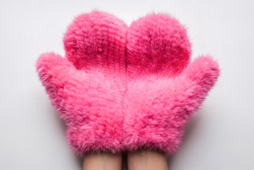 Fluffy mittens. Close up part of woman hands in fluffy pink mittens against white background