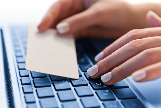 hands holding a credit card and using computer keyboard for online shopping
