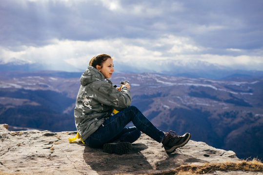 woman tourist drinks tea on a background of mountains