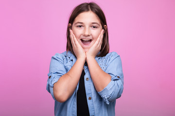 Close up portrait of surprised girl on pink background in studio