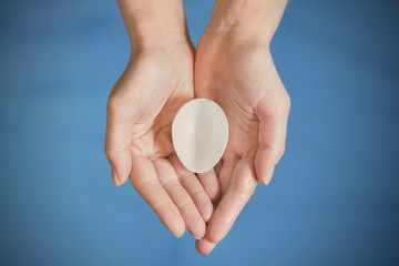 White eggshell in hands on a blue background