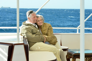 Smiling elderly couple resting on yacht