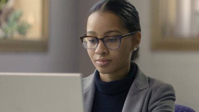 Young black female working at computer in a modern setting, close up