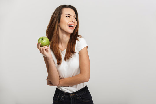 Portrait of a cheerful young woman holding green apple