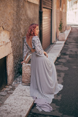 Fototapeta premium attractive elegant girl with pink hair in glamorous dress walking in Verona