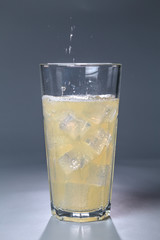 fizzy drink with ice in glass on gray background