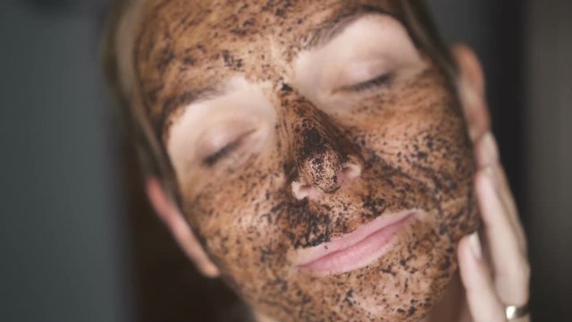 Closeup face of woman with facial coffee mask - video in slow motion