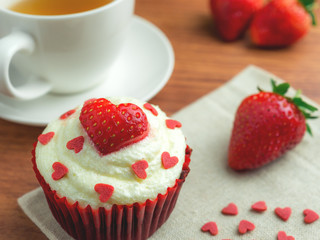 Close-up image of red velvet strawberry cup cake with tea cup, strawberry and heart shape sugar, Valentine concept