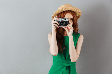 Redhead young lady photographer holding camera.