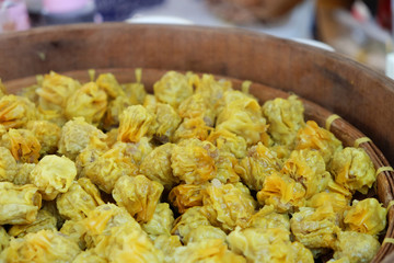 Many of hot yellow Chinese steamed dumplings in big wooden basket