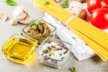 Food background, ingredients for cooking dinner.  Pasta spaghetti, vegetables, sauces and spices, grey stone background copy space