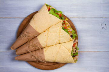 Wraps with chicken, tomatoes, lettuce, black beans, cheddar cheese and sweet corn. Tortilla, burritos, sandwiches twisted rolls. View from above, top, horizontal