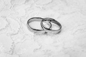 Wedding rings on white lace background, black and white photo