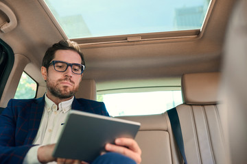 Young businessman using a digital tablet during his morning commute