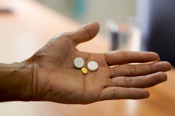 Pills and a glass of water on hand of man in health time
