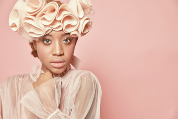 Close-up portrait of beautiful black woman with light hair and green eyes wearing powder pink tulle...