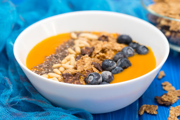 puree of mango with granola, chia and berries in white bowl