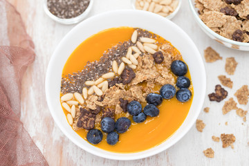 puree of mango with granola, chia and berries in white bowl
