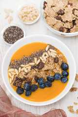 puree of mango with granola, chia and berries in white bowl