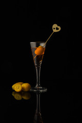Close-up of a liqueur with kumquat on a black background