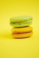 Yellow and green french sweets or macaroons on pastel yellow background. Creative food concept.