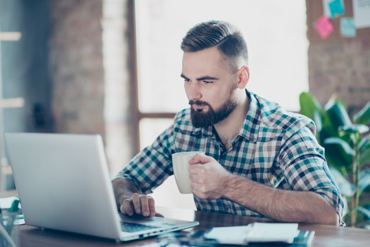 Concept Of Having A Break At Work. Concentrated Calm Peaceful Serious Office Worker  Watching Carefully A Video On The Internet Using His Laptop And Drinking Tea