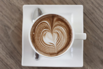 Top view cup of hot coffee latte art heart-shaped wooden floor.