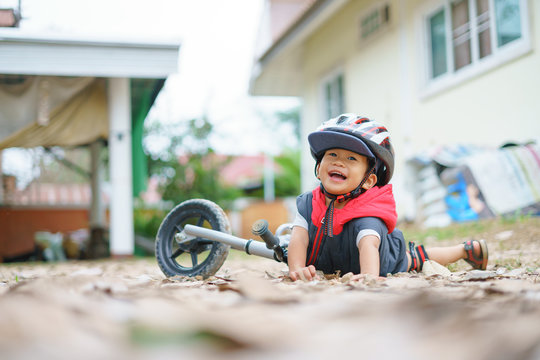 Asian boy about 2 years is riding baby balance bike and fall