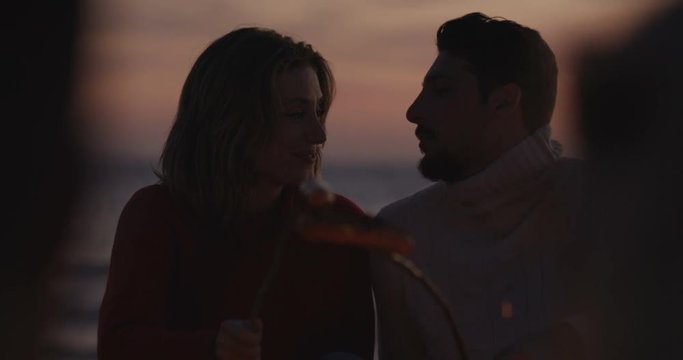 Young lovers smiling an night fire light. Shot on RED Helium 8K