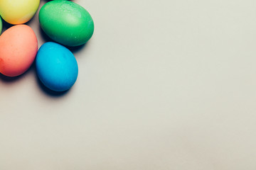 Four colored eggs in a corner on creamy background