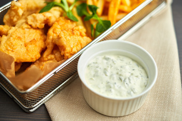 chicken nuggets with french fries and different sauces on wooden board,