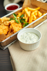 chicken nuggets with french fries and different sauces on wooden board,