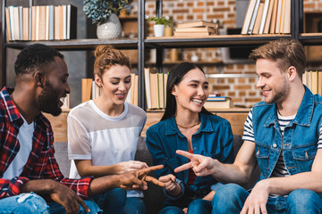 happy young multiethnic friends playing game of rock, paper, scissors