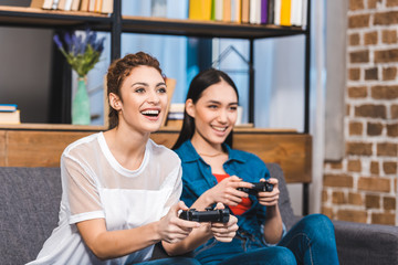 beautiful young multiethnic women playing with joysticks together