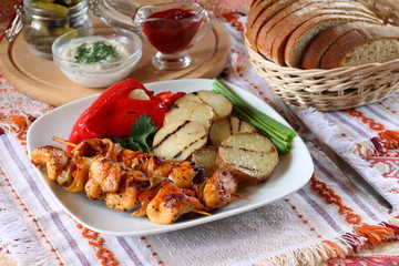 Chicken kebabs with grilled potatoes and vegetables.