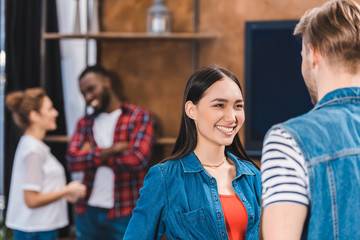 smiling young couple talking and looking at each other while friends standing behind