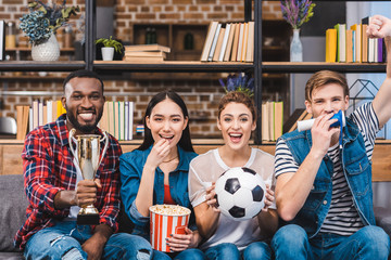happy young multiethnic friends watching soccer match together at home