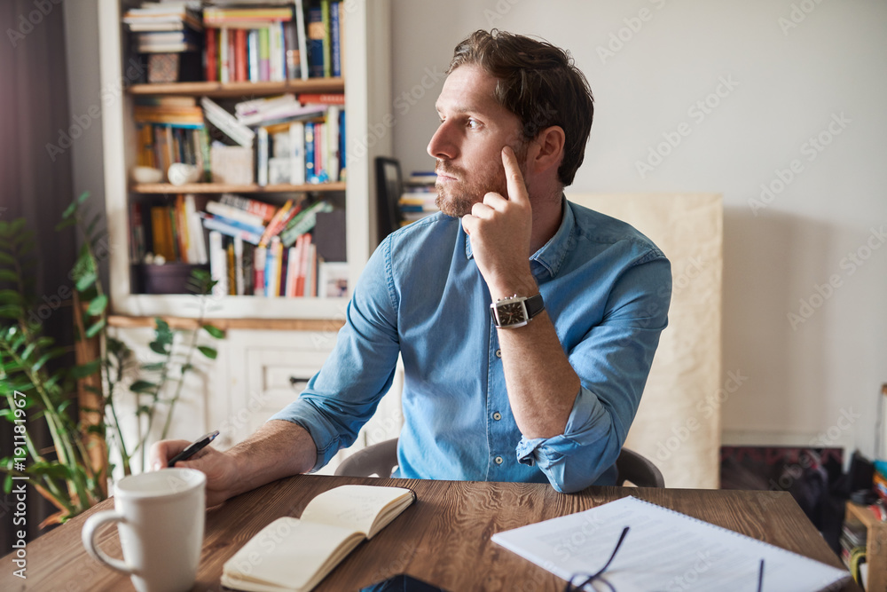 Wall mural young man deep in thought while working from home