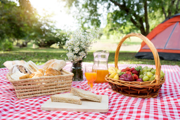 Fototapeta na wymiar picnic bread crossiant basket with fruit on red white cloth